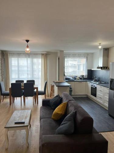 un salon avec un canapé marron et une cuisine dans l'établissement Super 3 pcs et Parking aux portes de Paris et stade de france à proximité des sites touristiques parisiens Montmartre , champs Élysée ,châtelet etc et des transports métro,RER ,wifi disponible, à Saint-Ouen