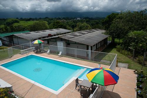 a swimming pool with an umbrella next to a house at La Mía Hospedaje in Armenia