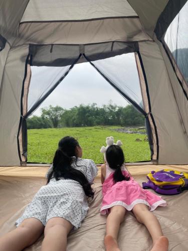 Kim Bôi的住宿－Camping Suối Cái，两个女孩躺在帐篷里,望着窗外