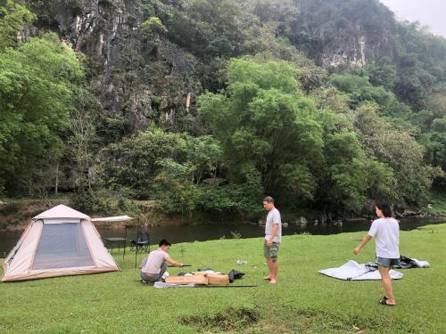 a group of people sitting in the grass next to a tent at Camping Suối Cái in Kim Bôi
