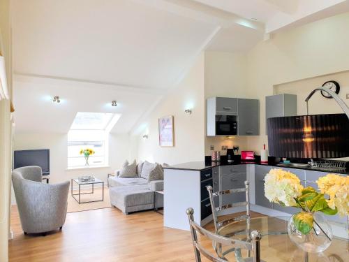 a kitchen and living room with a couch and a table at THE PENTHOUSE AT REGENT HOUSE Light and airy top floor with lift access 1 bedroom en-suite luxury apartment ULTRA CENTRAL LOCATION in Harrogate