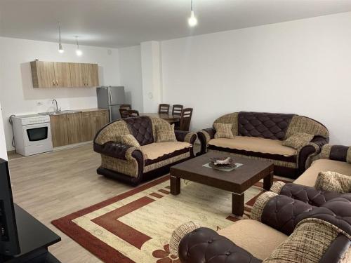 a living room with couches and a table and a kitchen at Banes me qera in Gjilan