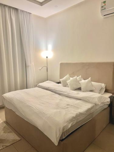 1 dormitorio con 1 cama con sábanas y almohadas blancas en غرفة وصالة بدخول ذاتي, en Riad