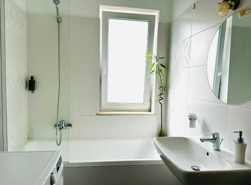 a white bathroom with a sink and a window at Bel Dom - The Cosy, 2 bedrooms family apartment in Cluj-Napoca