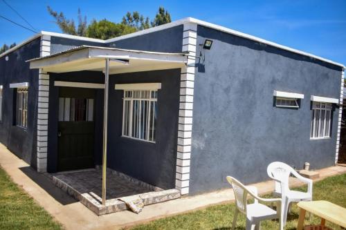 une petite maison bleue avec deux chaises et une table dans l'établissement Mella homes limuru, à Limuru