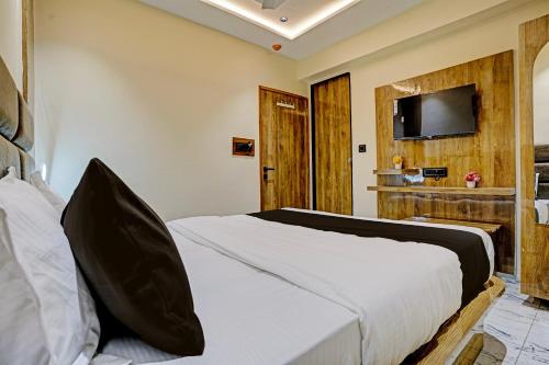 1 dormitorio con 1 cama y TV en la pared en OYO Flagship Hotel Meet Palace, en Ahmedabad