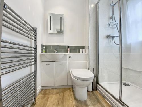 uma casa de banho branca com um WC e um chuveiro em The Annexe At Woodside 