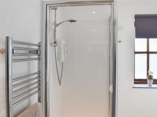 a glass shower door with a phone in a bathroom at Ty Ffair Mai Annexe in Llangwm-isaf