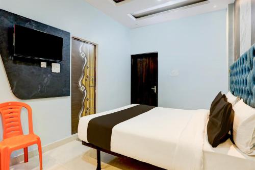 um quarto com uma cama e uma cadeira e uma televisão em OYO Flagship SHIVA VALLEY HOTEL em Varanasi