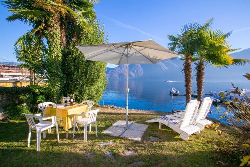 una mesa y sillas con sombrilla y el océano en Casetta al Lago, en Mezzegra
