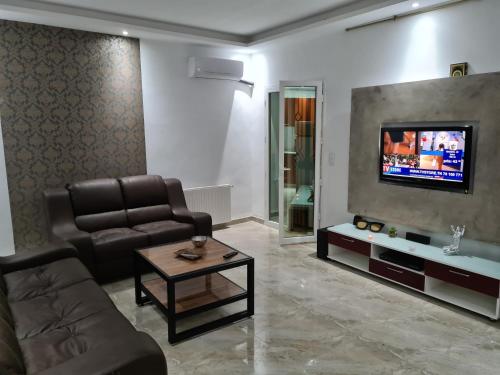 ein Wohnzimmer mit einem Sofa und einem TV in der Unterkunft Appartement 1 in Hammamet