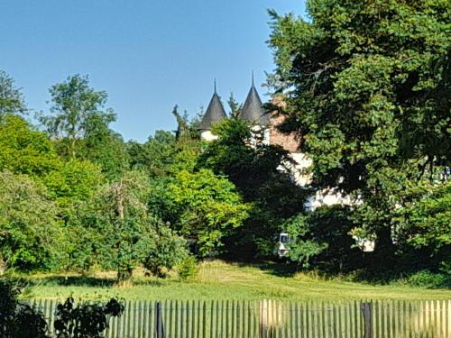 einen Garten mit einem Zaun und Bäumen sowie ein Gebäude in der Unterkunft Les Cottages du Chateau de Werde in Matzenheim