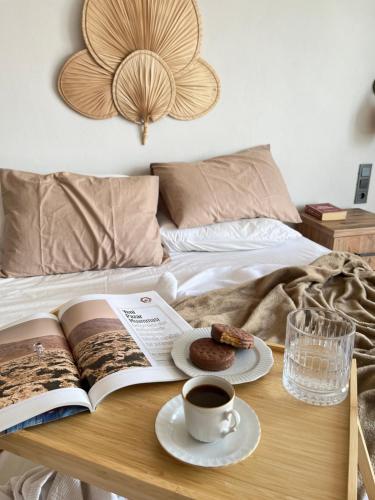a book and a cup of coffee and a plate of food on a bed at Aden Apart Otel in Fethiye