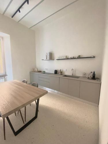 a white kitchen with a wooden table and a sink at Veneto Serviced Apartment by SupaStays in Rome