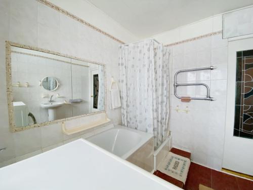 a bathroom with a tub and a sink and a mirror at Erdvus butas su balkonu šalia ežero ir stadiono in Visaginas