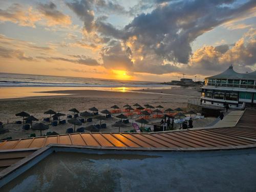 a sunset over a beach with umbrellas and the ocean at Peers Guest House in Cascais