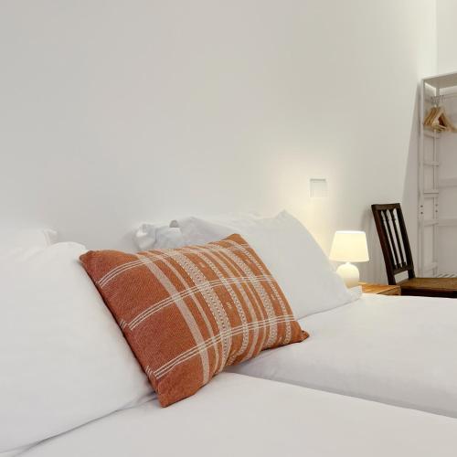 a white bed with a brown pillow on it at Senhora da Praça in Gavião