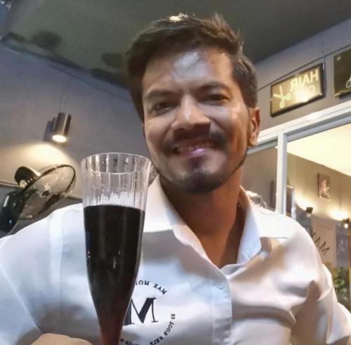 un homme tient un verre de vin dans l'établissement Max's Beach House, à Pattaya (sud)