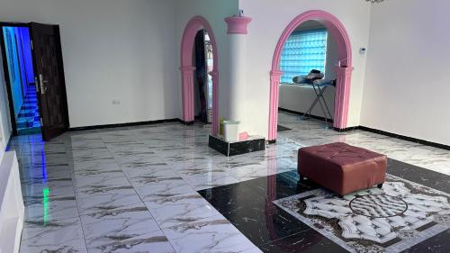 um quarto com arcos cor-de-rosa e uma mala no chão em KOFFY STAR GUEST HOUSE em Kumasi