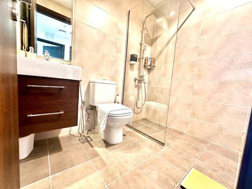 a bathroom with a toilet and a glass shower at Amazing 1Bedroom Plus Maid in Avencia at Damac Hills 2 in Dubai