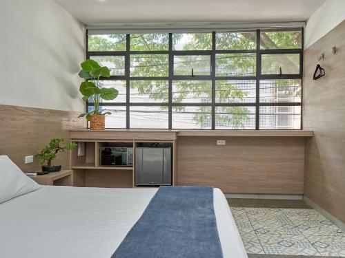 a bedroom with a bed and a large window at Stanza Hotel Medellin in Medellín