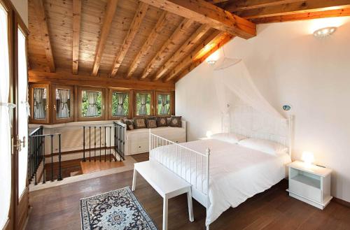 a bedroom with a white bed and a wooden ceiling at Antico Cascinale Lombardo in Lonato