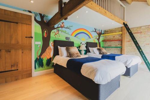 two beds in a room with a tree mural at Serene Luxury retreat near Newmarket, Exquisite amenities & Leisure in Brinkley