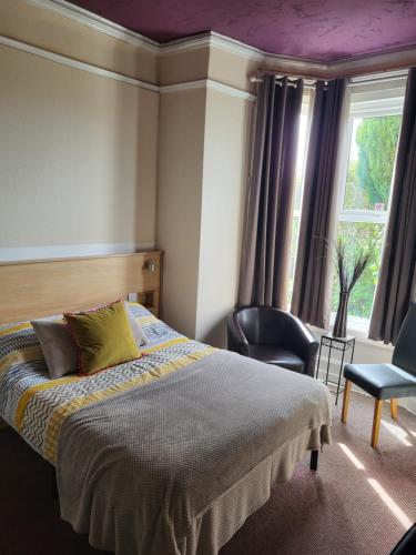 um quarto com uma cama, uma cadeira e uma janela em Station Guesthouse em Lancaster