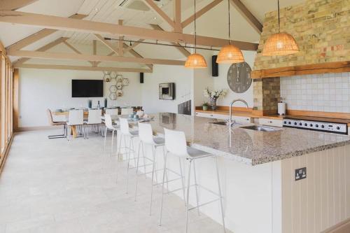 a kitchen with a bar with white stools at Newmarket Gem 5-Bedroom Home with Game Room and Cozy Spaces in Brinkley