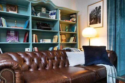 a brown leather couch in front of a book shelf at House w/Castle View Garden, Wine, Garage, Netflix in Budapest