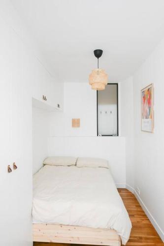 Cette chambre blanche comprend un lit et un miroir. dans l'établissement We Parisian The Marais Cozy Home, à Paris