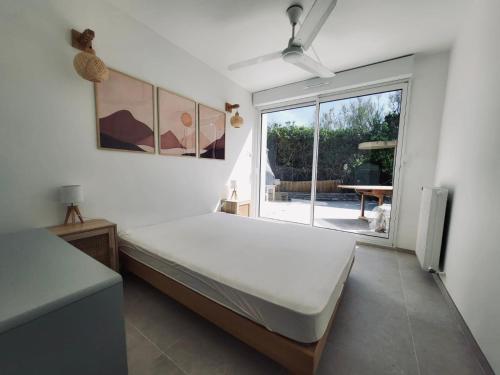 een slaapkamer met een bed en een groot raam bij VILLA BORD DE MER 6 COUCHAGES AVEC JARDIN ET GARAGE in La Grande-Motte