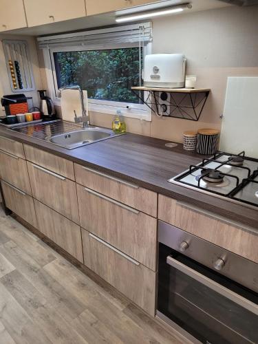 une cuisine avec un évier et une cuisinière dans l'établissement Mobilhome tout confort pour randonneurs, proche Saint-Malo, à 100 m de la plage et du GR34, à Saint-Coulomb