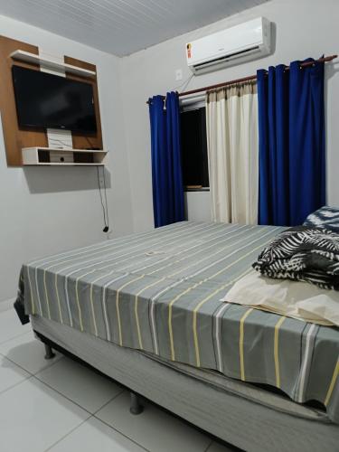 een slaapkamer met een bed met blauwe gordijnen en een televisie bij Home flat in Araguaína