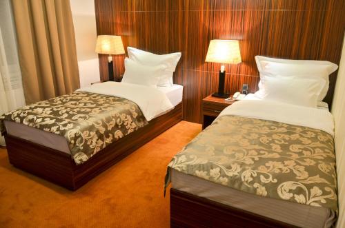 a hotel room with two beds and two lamps at Hotel JET SET Pale in Pale