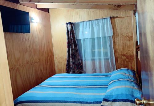a bedroom with a bed with a curtain and a window at Cabaña Duvi-du in Chile Chico