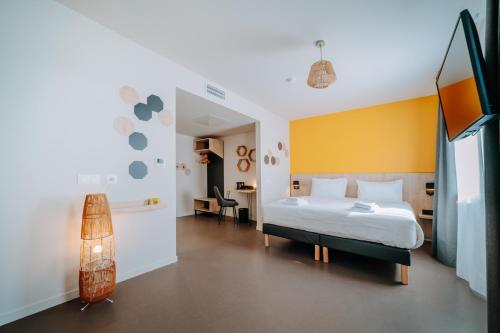 Beelodge Hotel Blois Centre في بلوا: غرفة نوم بسرير ابيض وجدار اصفر