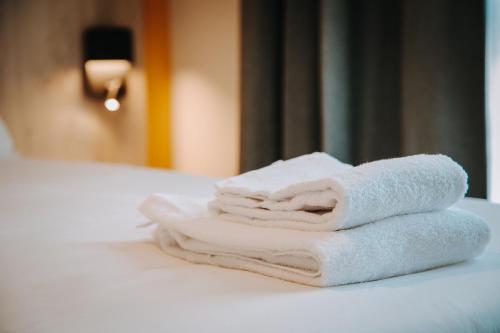 a pile of towels sitting on top of a bed at Beelodge Hotel Blois Centre in Blois