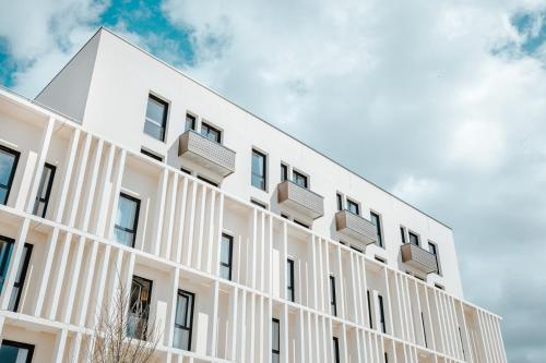 a white building with balconies on the side of it at Beelodge Hotel Blois Centre in Blois