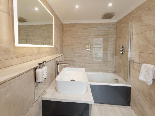 a bathroom with a sink and a bath tub at The Ship Inn - Winner Best Hotel Experience 2024 Visit Scotland in Gatehouse of Fleet
