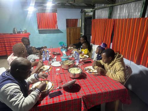 a group of people sitting at a table eating food at Leruk holiday home in Masai Mara