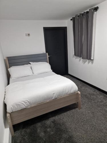 a bedroom with a large bed with white sheets at CKB Flat- comfort, cosy, and secure! in Codsall