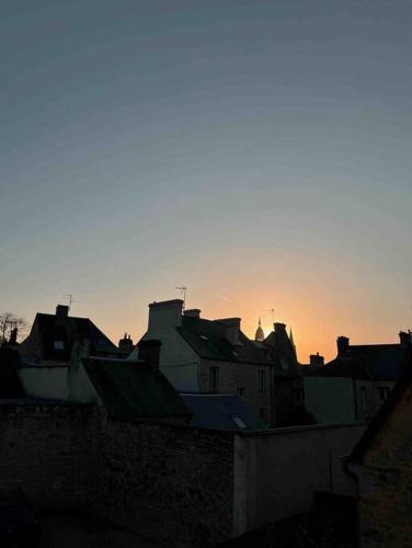 un groupe de bâtiments au coucher du soleil en arrière-plan dans l'établissement Appartement au centre ville de Bayeux, à Bayeux