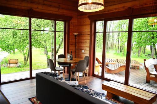 a living room with a table and chairs and windows at Kaimukas - namelis prie ežero keturiems in Dvarčėnai