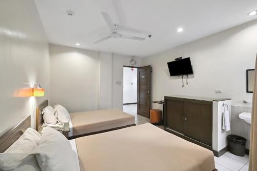 a hotel room with a bed and a tv at Governor Forbes Inn - Manila City Center in Manila