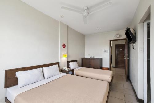 a hotel room with two beds and a television at Governor Forbes Inn - Manila City Center in Manila