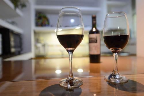 two wine glasses sitting on a table with a bottle of wine at El Refugio in Ciudad Lujan de Cuyo