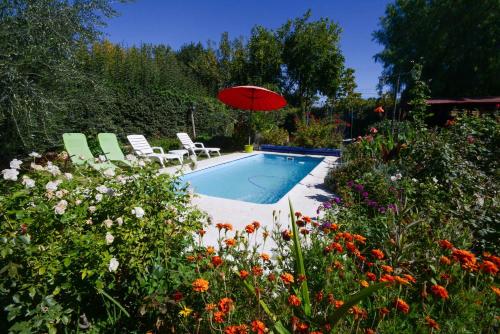 a swimming pool with a red umbrella and chairs at El Refugio in Ciudad Lujan de Cuyo