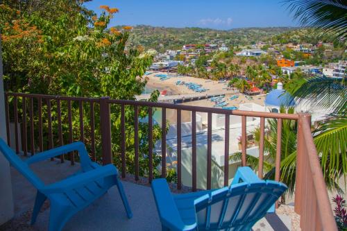 a balcony with blue chairs and a beach at Hotel Casa Rush in Puerto Ángel