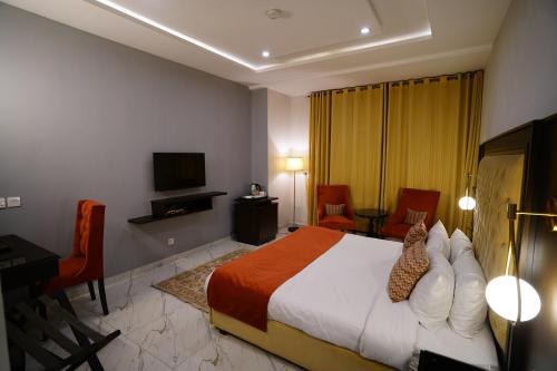 a bedroom with a bed and a desk and a television at Faletti’s Grand MM Alam Road in Lahore